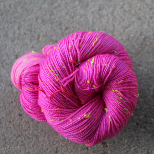 Pink yarn skein with speckles on a gray surface