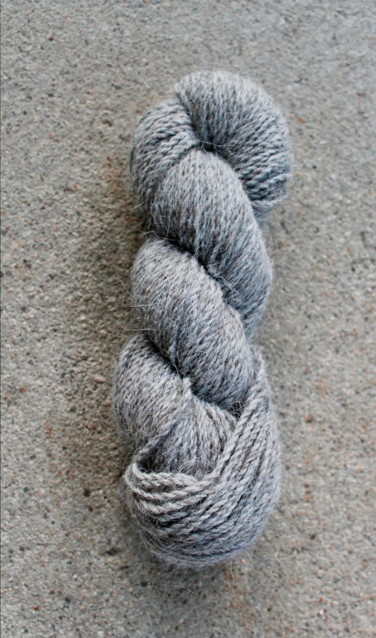 Gray skein of yarn on a textured gray surface