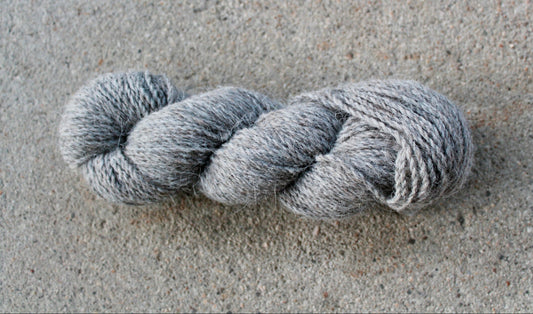 Gray skein of yarn on a textured gray surface