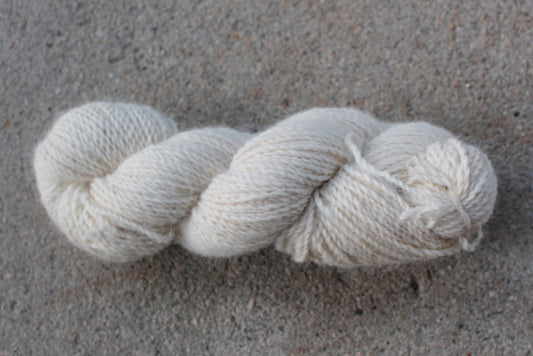 Single skein of natural worsted yarn against a speckled backdrop