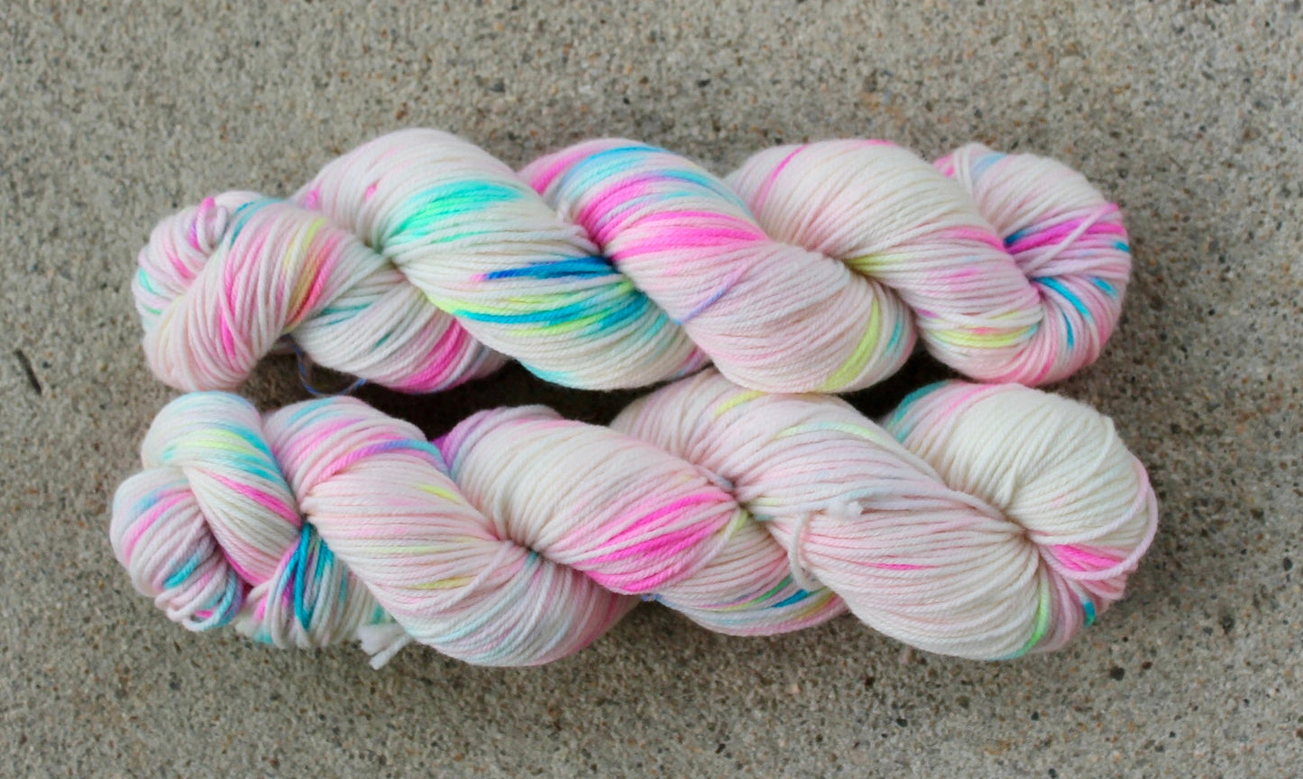 Two skeins of colourful yarn on a concrete surface