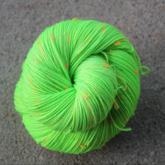 Green skein of yarn with orange speckles on a gray surface